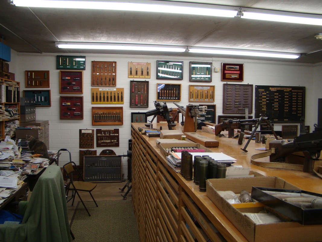 Framed ammunition display boards covering a wall above laboratory cabinets.