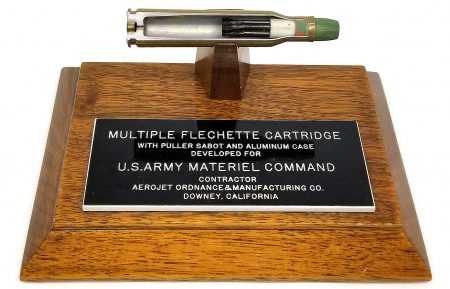 Lot 30 - Aerojet factory display on wood base, “Multiple Flechette Cartridge with puller sabot and aluminum case, etc.” 25° section of cartridge. Ex-Woodin collection. $165-210