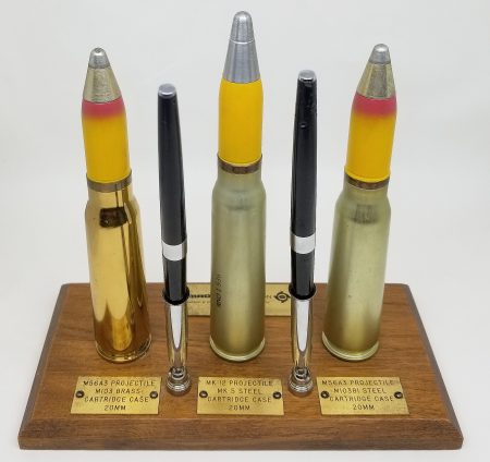 Lot 62 - Amron Corporation factory desk set display of three 20mm cartridges: M56A3 Projectile in M103 brass case, MK12 projectile in MK 5 steel case, and M56A3 projectile in M103B1 steel case. Wood base and two pens. Ex-Woodin collection. $275-350
