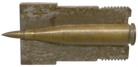 Lot 90 - Cal. .30 Super High Velocity dummy cartridge with T3 solid brass bullet. HWS Vol. I Revised, pages 274-275, Fig. 412. “CAL 50 FA 30.” Primer pocket drilled out. Cartridge is set inside a 180° section of the gun breech it was fired in. Ex-Woodin collection. $500-750
